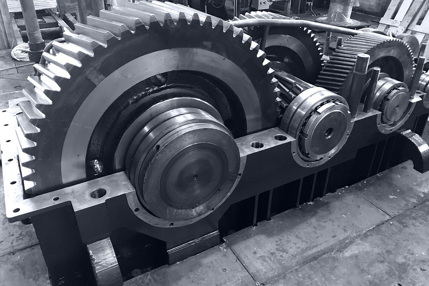 large gearbox open, showing the gears, the whole set attached to a shaft with a cap, industrial environment, photo in black and white with bluish tone